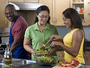 Family in kitchen preparing salad.