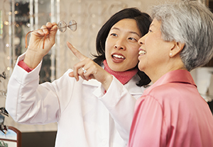 Optician showing eyeglasses to woman.