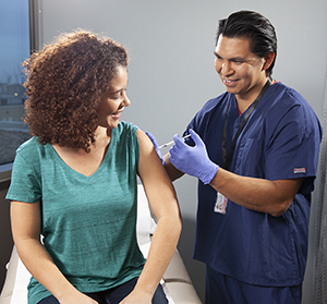 Healthcare provider giving woman injection in arm.