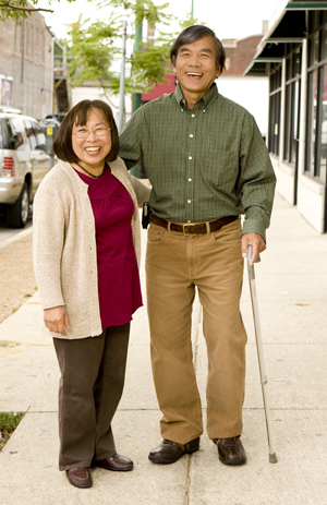 Man with cane walking on city street with woman.