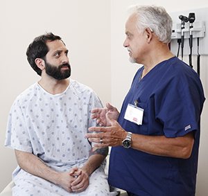 Man talking to healthcare provider in exam room.