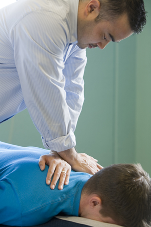 Chiropractor massaging a man's back.