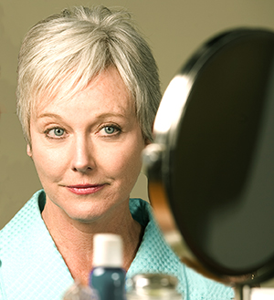 Woman with short hair looking in mirror.