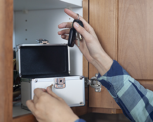 Woman putting keys in locking box in kitchen cabinet.
