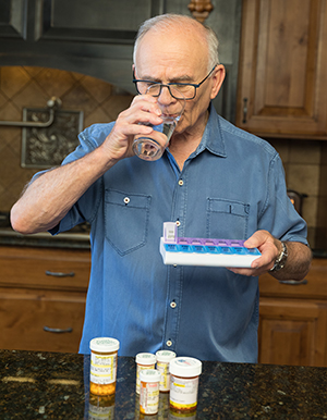 Un hombre toma pastillas en la cocina.