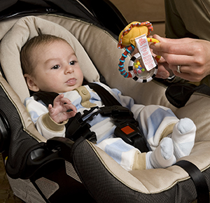 Woman giving toy to baby in carrier.